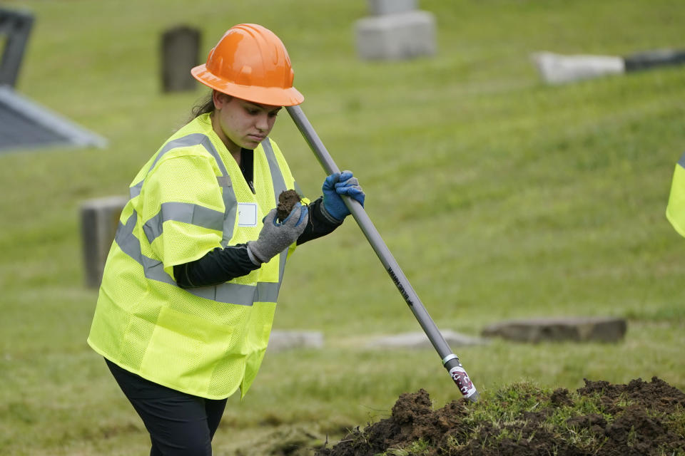 A worker examines a piece of dirt as excavation begins at Oaklawn Cemetery in a search for victims of the Tulsa Race Massacre believed to be buried in a mass grave, Tuesday, June 1, 2021, in Tulsa, Okla. (AP Photo/Sue Ogrocki)
