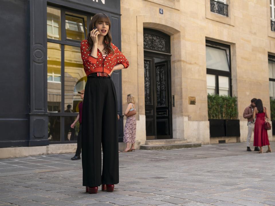 Lily Collins on the phone outside in "Emily in Paris."