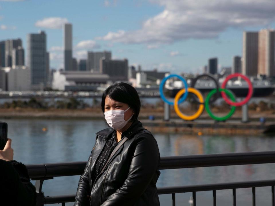 A tourist poses in front of the Olympic rings in Tokyo wearing a face mask amid the coronavirus outbreak: AP