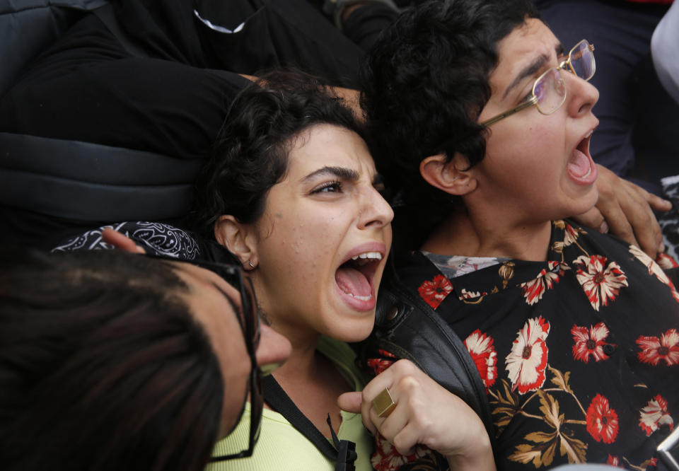 Anti-government protesters lie on a highway road, as they scream and hold each others after riot police arrive to remove them and open the road, in Beirut, Lebanon, Saturday, Oct. 26, 2019. Lebanese security forces pushed and dragged away protesters who refused to move from roadblocks in central Beirut on Saturday, to reopen roads closed during a campaign of civil disobedience. (AP Photo/Hussein Malla)