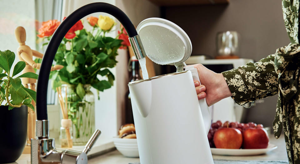 Woman filling a white kettle at a tap