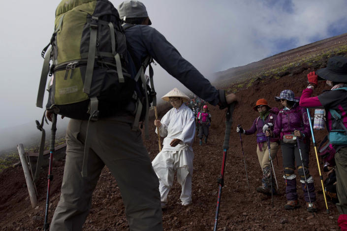 In this Sunday, Aug. 11, 2013 photo, hikers make their way down the slopes of Mount Fuji in Japan. The Japanese cheered the recent recognition of Mount Fuji as a UNESCO World heritage site, though many worry that the status may worsen the damage to the environment from the tens of thousands who visit the peak each year. (AP Photo/David Guttenfelder)