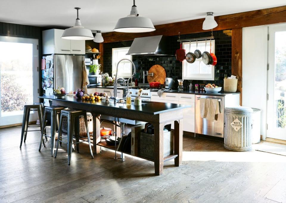 a modern farmhouse style kitchen with oversize white pendant lighting and an island with black countertops