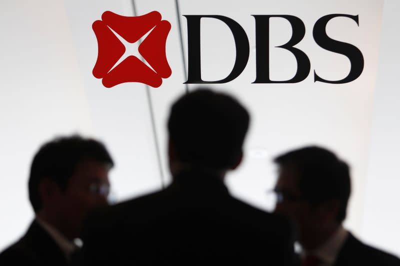 People talk next to a DBS logo at a DBS function in Singapore