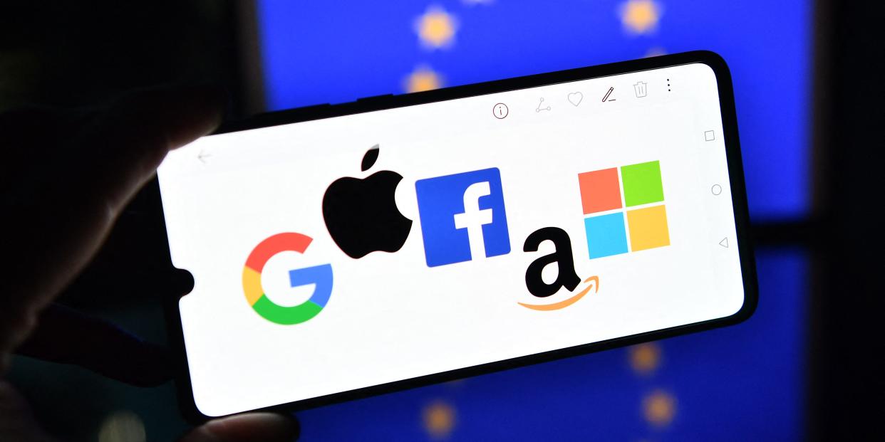 An illustration picture taken in London on December 18, 2020 shows the logos of Google, Apple, Facebook, Amazon and Microsoft displayed on a mobile phone with an EU flag displayed in the background.