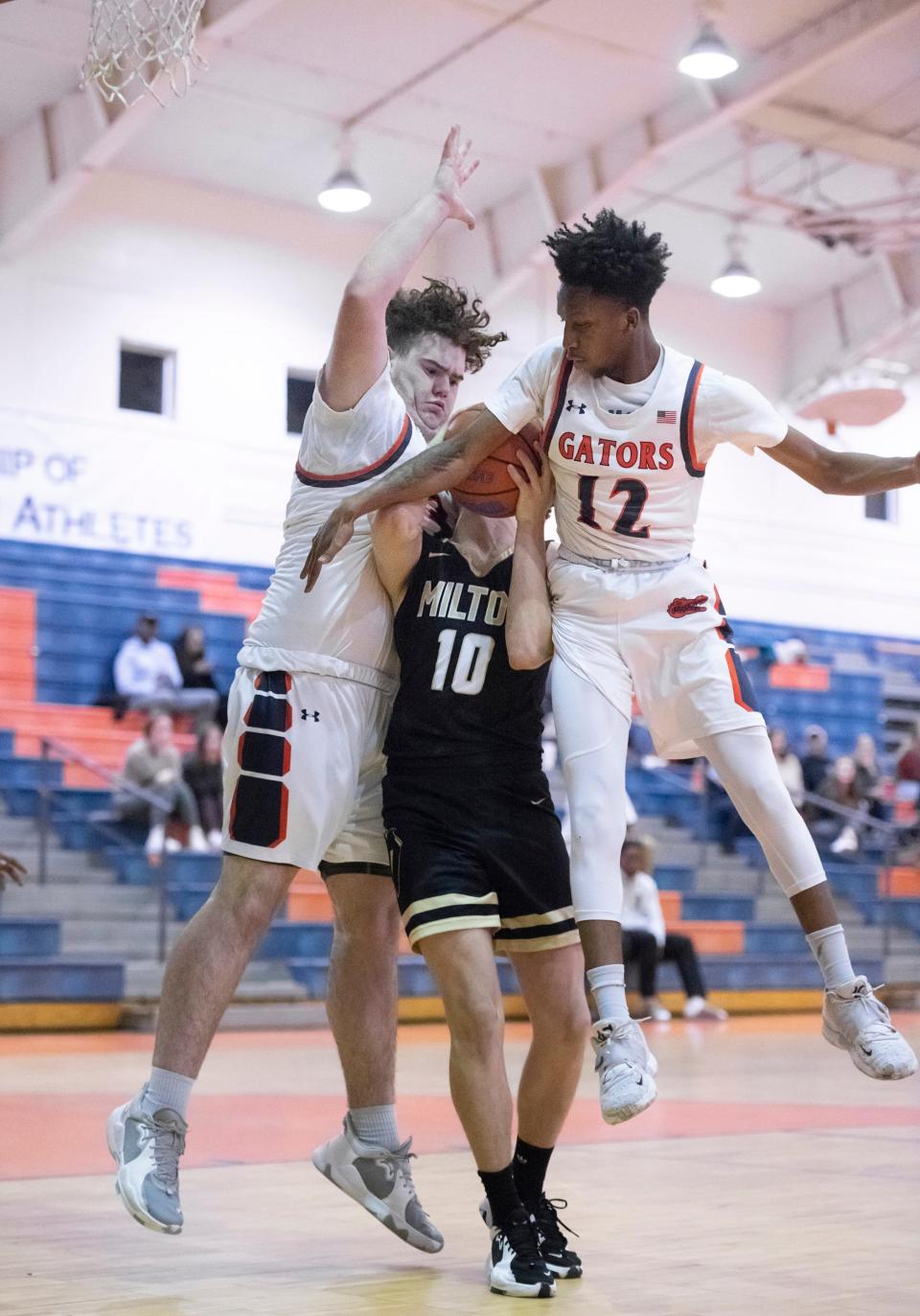 Corey Scott (32) and Keondre Averhart (12) converge on Hayden Mock (10) as he attempts to shoot during the Milton v Escambia boys basketball game at Escambia High School in Pensacola on Thursday, Jan. 6, 2022.