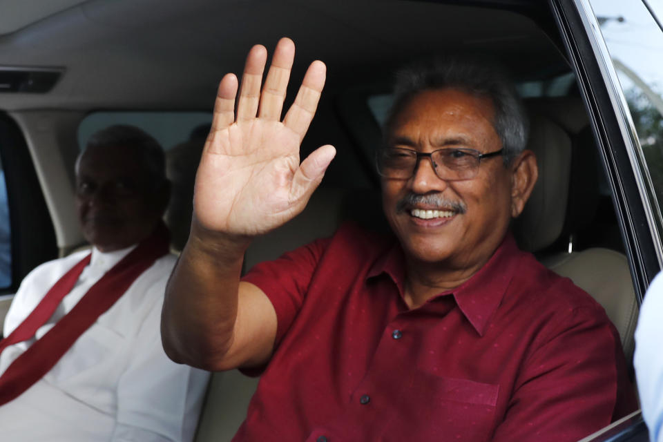 Sri Lanka's former Defense Secretary and president elect Gotabaya Rajapaksa in red, waves to supporters as he leaves the election commission after the announcement of his victory with elder brother Chamal, in white, in Colombo, Sri Lanka, Sunday, Nov.17, 2019. Rajapaksa, revered by Sri Lanka's ethnic majority for his role in ending a bloody civil war but feared by minorities for his brutal approach, declared victory Sunday in the nation's presidential election. (AP Photo/Eranga Jayawardena)