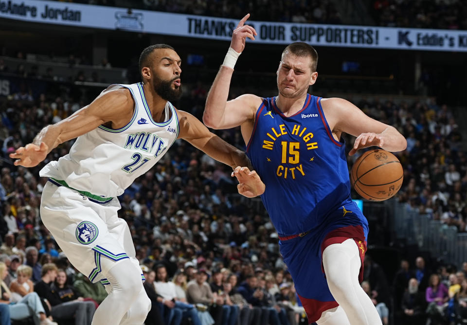 Denver Nuggets center Nikola Jokic, right, draws a foul on Minnesota Timberwolves center Rudy Gobert while driving to the basket in the first half of an NBA basketball game Friday, March 29, 2024, in Denver. (AP Photo/David Zalubowski)