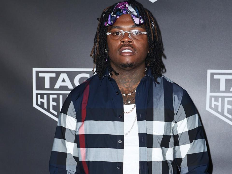 Gunna poses for photos in a plaid jacket and pants and matching headband.