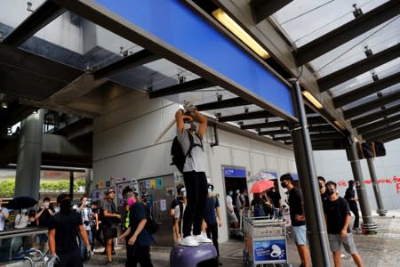 An anti-extradition bill protester breaks a security camera outside the terminal at Hong Kong International Airport, in Hong Kong