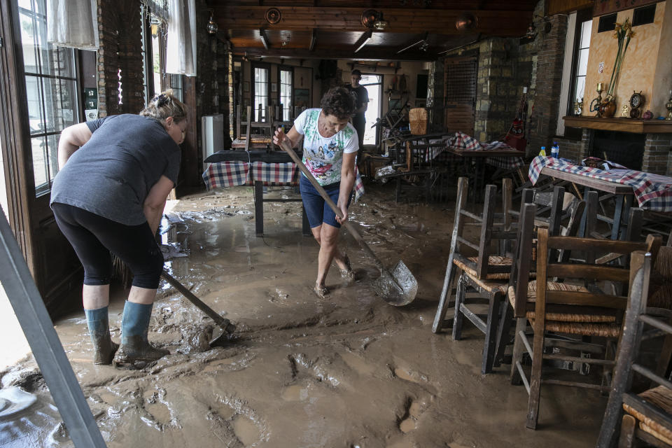 Locals try to move water and mud from a tavern following a storm at the village of Politika, on Evia island, northeast of Athens, on Sunday, Aug. 9, 2020. Five people have been found dead and dozens have been trapped in their homes and cars from a storm that has hit the island of Evia, in central Greece, police say. (AP Photo/Yorgos Karahalis)