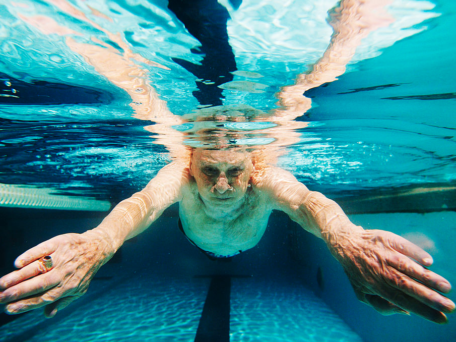 An elderly man swims