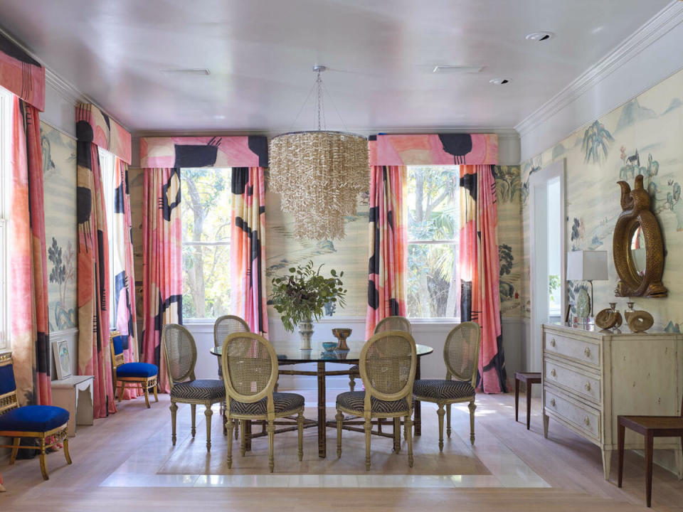 Coral accents unite this dining room’s 1920s wallpaper panels with the graphic modern window treatments 