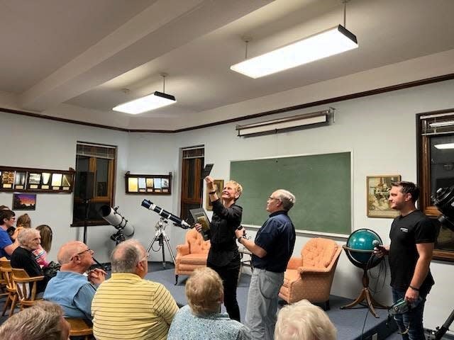 Drake University professor Herb Folsom presents Peggy Whitson with an original print of Comet Morehouse and an old glass slide of the comet during a Capital City Pride Fireside Chat event on Sept. 22, 2023.