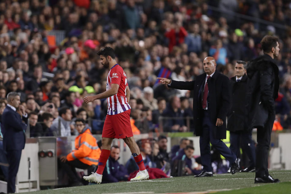 Atletico forward Diego Costa passes his coach Diego Simeone, right, as walks off the pitch after receiving a red card for insulting referee Jesus Gil Manzano during a Spanish La Liga soccer match between FC Barcelona and Atletico Madrid at the Camp Nou stadium in Barcelona, Spain, Saturday April 6, 2019. (AP Photo/Manu Fernandez)