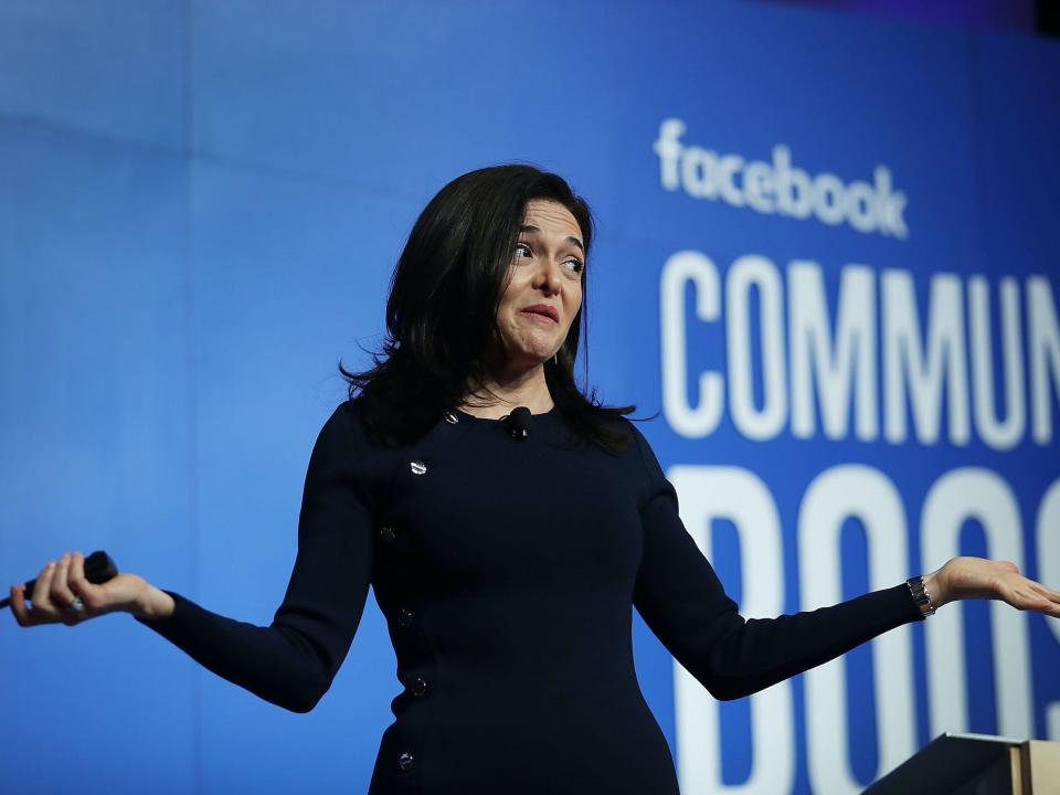 Sheryl Sandberg, Meta COO, shrugs while standing on stage at a Facebook event