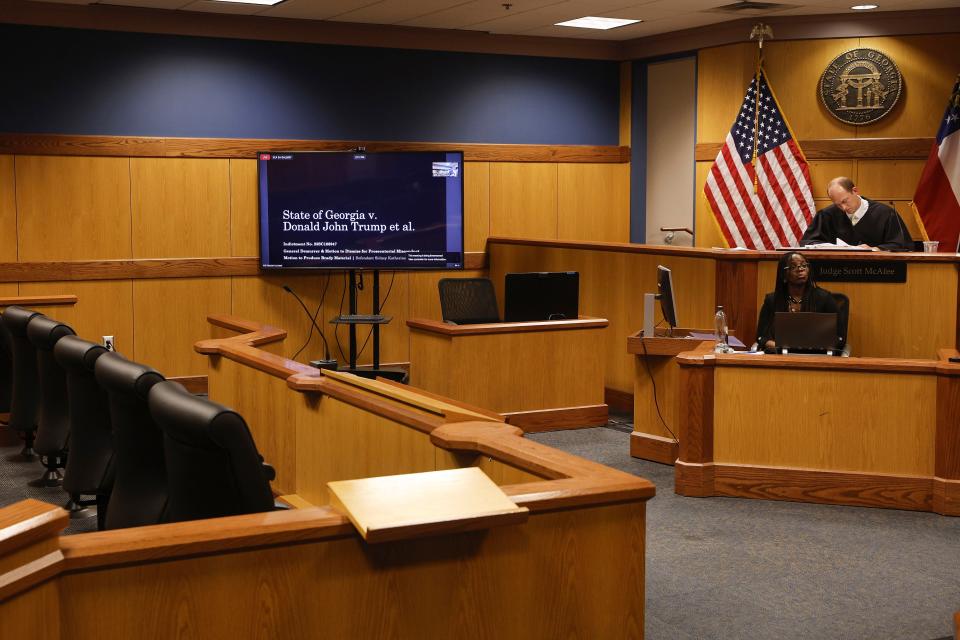 The chairs in the jury box, left, are empty as Fulton County Superior Court Judge Scott McAfee, top right, listens during a motions hearing address from the attorney for defendant Sidney Powell, in Atlanta, Thursday, Oct. 5, 2023. Nineteen people, including former President Donald Trump, were indicted in August and accused of participating in a wide-ranging illegal scheme to overturn the results of the 2020 presidential election. (Erik S. Lesser/Pool Photo, via AP)