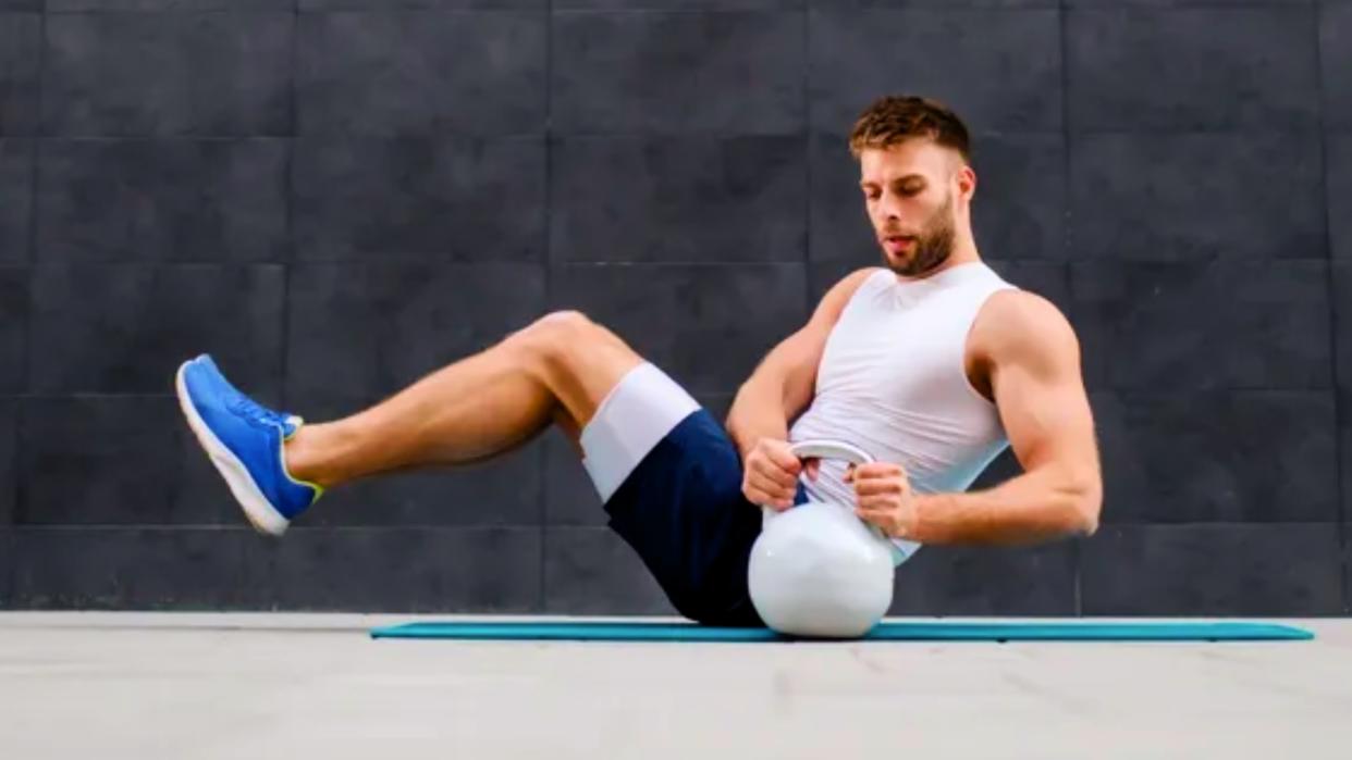  Man doing kettlebell ab workout. 