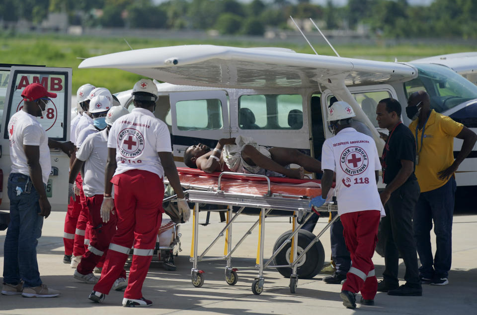 An earthquake victim who was airlifted from the city of Les Cayes, is moved to an ambulance by health workers, at the local terminal of the Toussaint Louverture airport in Port-au-Prince, Haiti, Sunday, Aug. 15, 2021. The death toll from the magnitude 7.2 earthquake in Haiti soared on Sunday as rescuers raced to find survivors amid the rubble ahead of a potential deluge from an approaching tropical storm. (AP Photo/Fernando Llano)