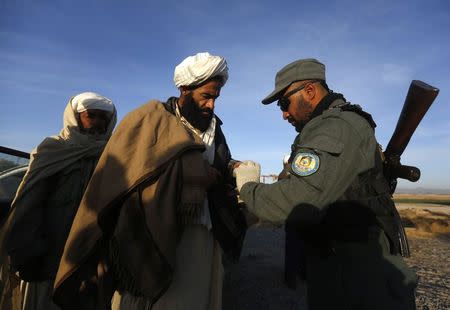 An Afghan policeman inspects passengers at a checkpoint on the outskirts of Farah province February 4, 2015. REUTERS/Omar Sobhani