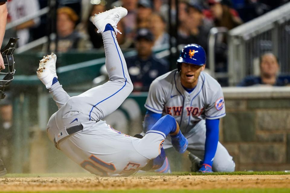 New York Mets' Eduardo Escobar (10) rolls over after scoring on a sacrifice fly with Brandon Nimmo at right, during the sixth inning of a baseball game against the Washington Nationals at Nationals Park, Tuesday, May 10, 2022, in Washington.