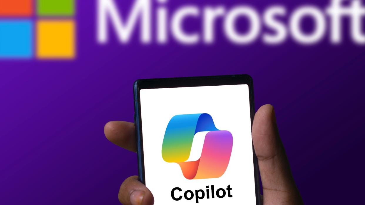  Microsoft Copilot app running on a phone with Microsoft logo in background. 