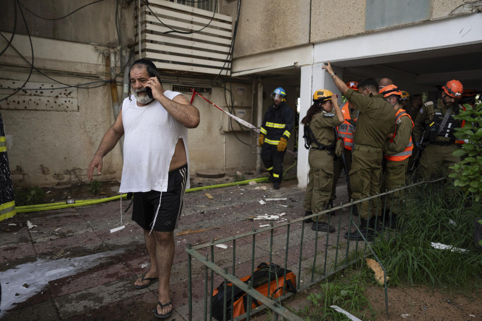 An Israeli man talks on his phone next to a building struck by a rocket fired from Gaza, in Tel Aviv, Israel, Friday, Oct. 27, 2023. (AP Photo/Oded Balilty)