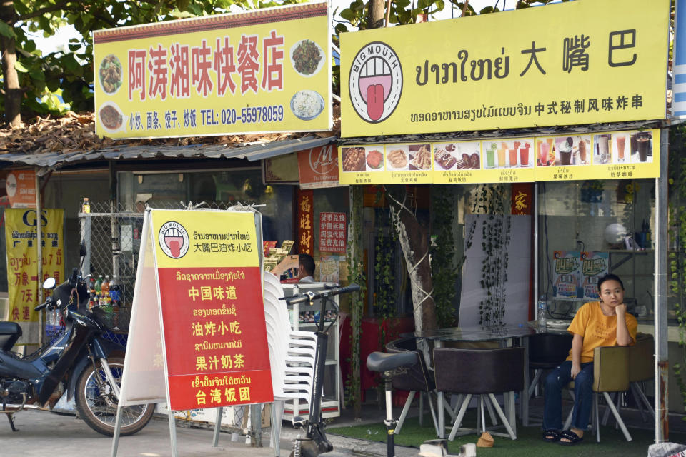 A restaurant clerk rests at a Chinese restaurant in Vientiane in Feb. 11, 2020. Laos locked down its capital and closed its international borders to most traffic Thursday, April 22, 2021, after identifying a COVID-19 cluster connected to its bigger neighbor Thailand. (Kyodo News via AP)