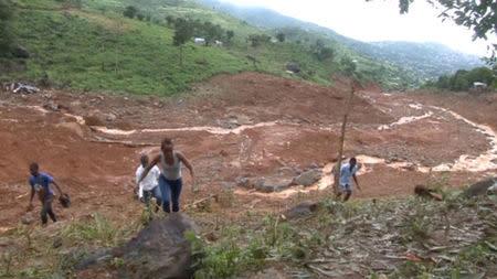 People walk up the mudslide in the mountain town of Regent, Sierra Leone August 15, 2017 in this still image taken from a video. via Reuters TV