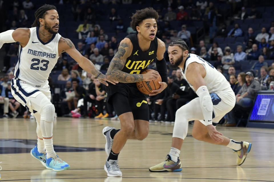 Utah Jazz guard Keyonte George (3) handles the ball between Memphis Grizzlies guard Derrick Rose (23) and forward David Roddy in the first half of an NBA basketball game Wednesday, Nov. 29, 2023, in Memphis, Tenn. (AP Photo/Brandon Dill)