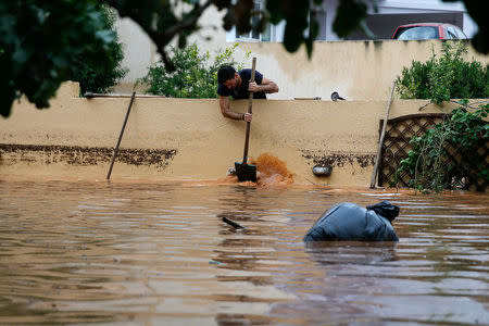 A man removes water from the yard of a house, following flash floods which hit the town of Magoula, Greece, June 27, 2018. REUTERS/Costas Baltas