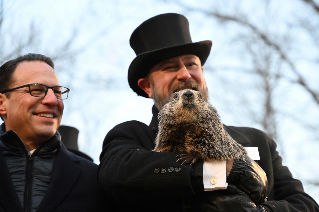 Pennsylvania Gov. Josh Shapiro looks on as A.J. Dereume holds Punxsutawney Phil last February before the groundhog predicted six more weeks of winter. PETA is hoping to replace the 137-year-old tradition with a giant gold coin flip.