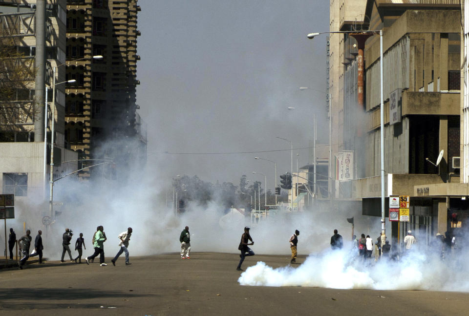 Protesters run from teargas fired by riot police during protests in Harare, Friday, Aug, 16, 2019. Zimbabwe's police fired tear gas to disperse anti-government protesters in the center of the capital, Harare, Friday morning. A few hundred demonstrators gathered in Africa Unity Square, despite a police ban on the protest that was upheld by Zimbabwe's High Court. (AP Photo/KB Mpofu)