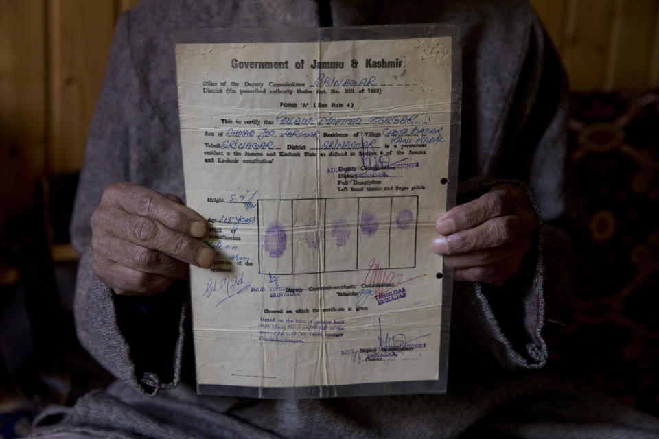 Ghulam Mohammad Zargar, an elderly Kashmiri man shows his domicile document locally know as "State Subject" which was only held by permanent residents of Jammu and Kashmir in Srinagar, Indian controlled Kashmir, Thursday, Oct. 31, 2019. Zargar said, with the abrogation of article 370 this document is gone and with it Kashmiri identity has also gone. India on Thursday formally implemented legislation approved by Parliament in early August that removes Indian-controlled Kashmir's semi-autonomous status and begins direct federal rule of the disputed area amid a harsh security lockdown and widespread public disenchantment. (AP Photo/ Dar Yasin)