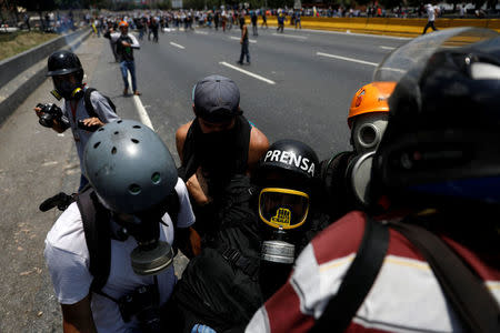 A member of the media is helped during a rally against Venezuela's President Nicolas Maduro's government in Caracas, Venezuela April 10, 2017. REUTERS/Carlos Garcia Rawlins