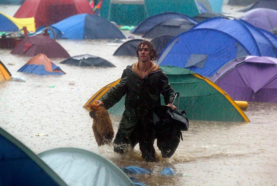 One unlucky festival-goer traipses through a sea of water and abandoned tents during 2005’s  festival floods (Getty Images)