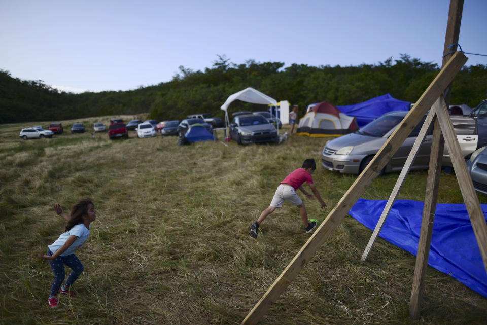 In this Friday, Jan. 10 photo, children play on a hay farm where residents from the Indios neighborhood of Guayanilla, Puerto Rico, have set up shelter after earthquakes and amid aftershocks in Guayanilla, Puerto Rico. A 6.4 magnitude quake that toppled or damaged hundreds of homes in southwestern Puerto Rico is raising concerns about where displaced families will live, while the island still struggles to rebuild from Hurricane Maria two years ago. (AP Photo/Carlos Giusti)