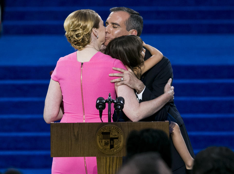 FILE - In this July 1, 2017, file photo, Los Angeles Mayor Eric Garcetti kisses his wife, Amy Elaine Wakeland, and their daughter, Maya, as he is sworn in for his second term at Los Angeles City Hall. Garcetti said Thursday, Dec. 17, 2020, that his 9-year-old daughter, Maya, has tested positive for COVID-19, and that he and his wife are quarantining at home. Garcetti said his daughter Maya felt ill on Monday, developed a fever and tested positive for COVID-19. He said he and his wife have tested negative. (AP Photo/Damian Dovarganes, File)