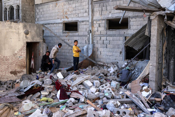 Men and a boy inspect the site of a building that was hit by Israeli bombardment in Rafah in the southern Gaza Strip on 8 May 2024 (AFP via Getty Images)
