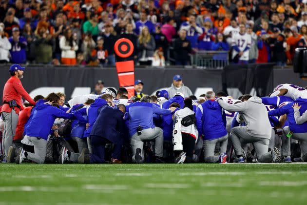Buffalo Bills players and staff kneel together in solidarity after Damar Hamlin collapsed on the field during a cardiac arrest. 
