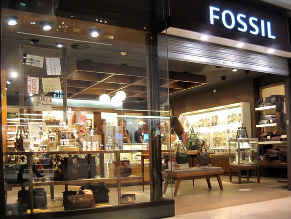 Fossil store location as viewed from outside, with lighted displays and various items in showcases.