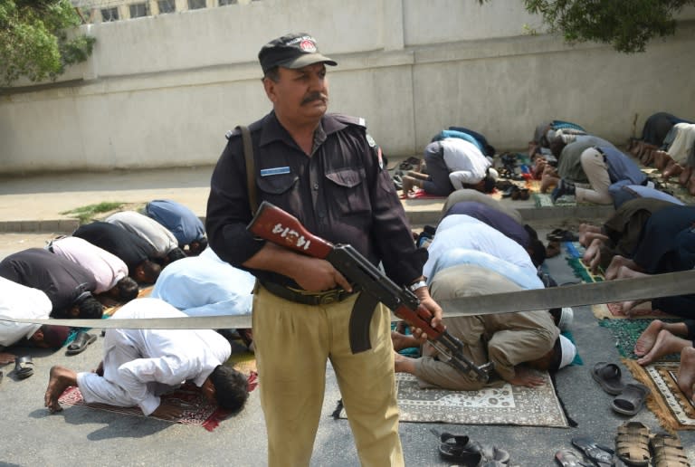 A Pakistani policeman stands guard as Muslims offer Friday prayers on a street in Karachi, on February 17, 2017