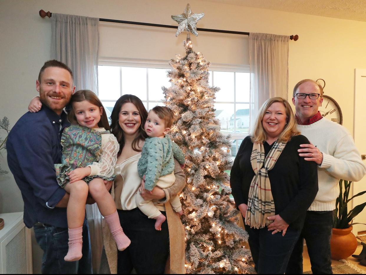 Nick and Cassie Horvath hold their children, LJ,  5, and Graham, 9 months, as they gather near the Christmas tree with surrogate grandparents Lara and Rich Wilson at the Horvath's Lafayette Township home.