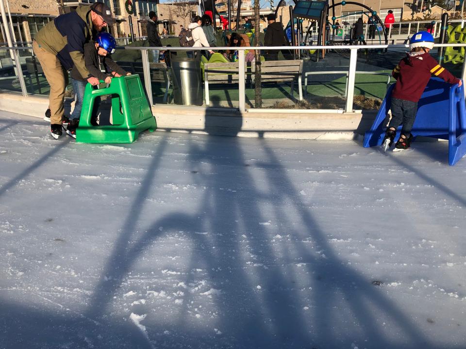 The photographer's bike casts a shadow on ice shavings, hastened by the sun, as skaters pass on Feb. 26, 2023, at the Howard Park ice path in South Bend.
