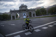 Una mujer espera un cambio de luz frente a la Puerta de Alcalá en Madrid el 25 de abril del 2020. La pandemia de coronavirus está dando nuevo impulso a las bicicletas como alternativa al trasporte público. (AP Photo/Manu Fernández)