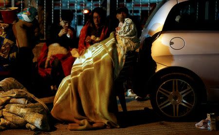 A woman covers herself with a blanket near a car as she prepare to spend the night in the open following an earthquake in Amatrice, central Italy, August 24, 2016. REUTERS/Stefano Rellandini