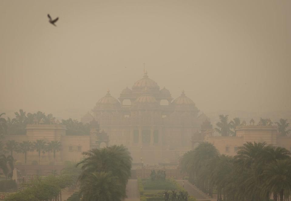 A bird flies next to the smog-covered Akshardham temple (Reuters)
