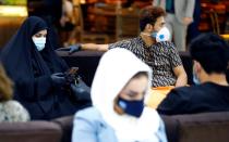 Passengers wearing protective masks sit at the departure hall after the reopening of Baghdad International Airport, where flights halted due to the coronavirus disease (COVID-19) outbreak, in Baghdad