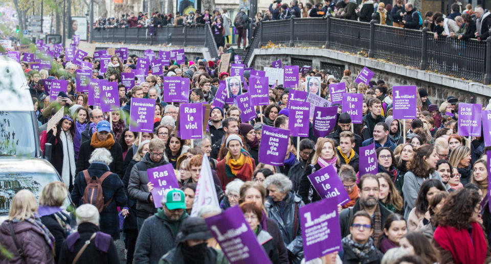 Thousands of men and women holding banners in Paris protest against violence against women.