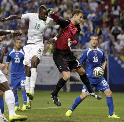 Bosnia goalkeeper Asmir Begovic, center, deflects a head ball away from Ivory Coast&#39;s Lacina Traore (18) as Bosnia&#39;s Toni Sunjic (15) watches during the first half in an international friendly soccer match Friday, May 30, 2014, in St. Louis. (AP Photo/Jeff Roberson)